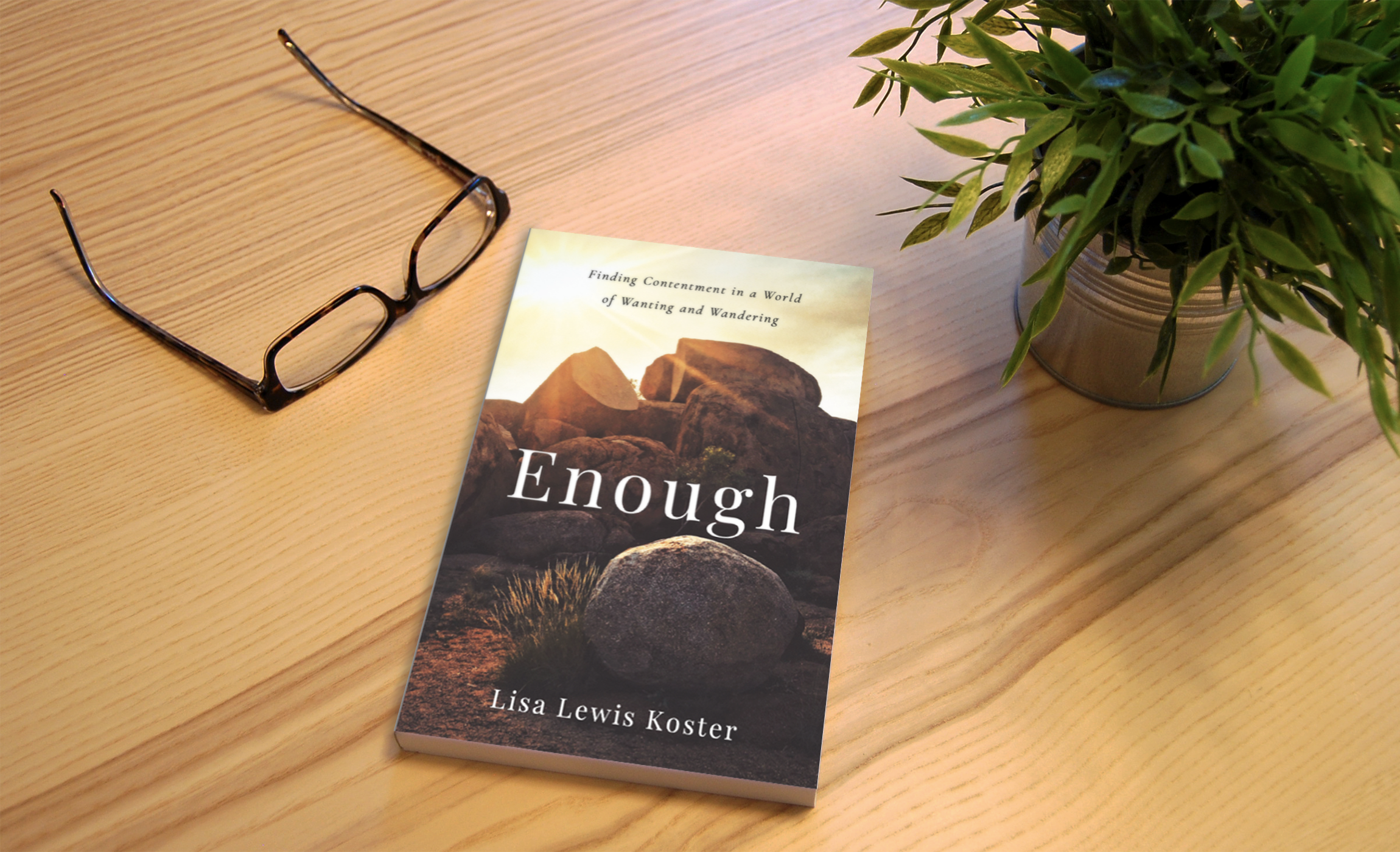 Enough by Lisa Lewis Koster on a wooden table beside a pair of glasses